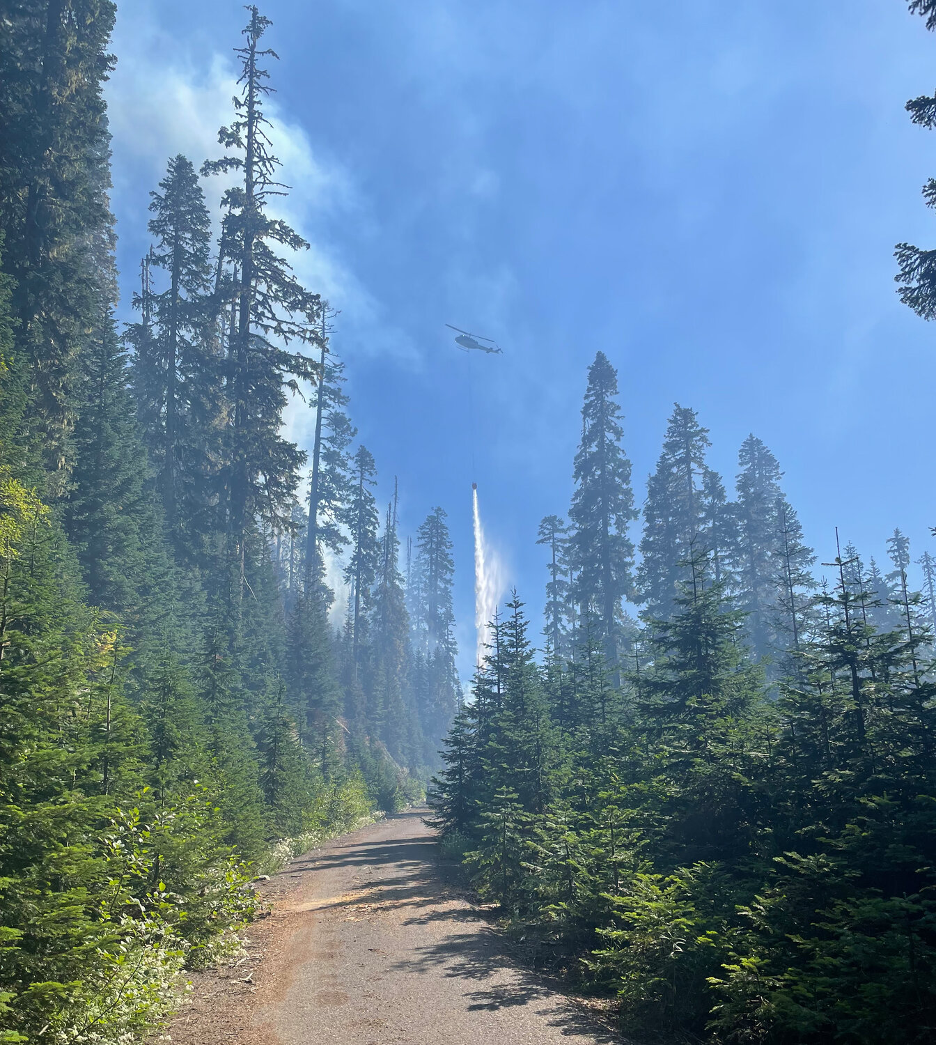 Amid smoke, a helicopter drops buckets of water over the second Spencer Quartz Fire in the Gifford Pinchot National Forest, the largest of the Cowlitz Complex Fires, which were set by a lightning storm on Aug. 25.